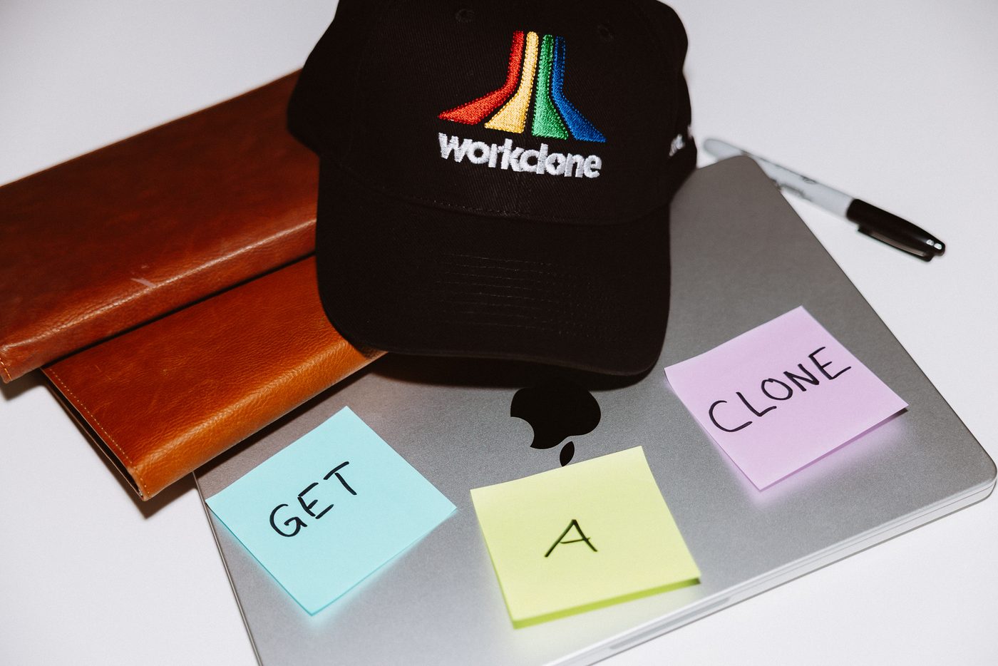 A WorkClone cap and “get a clone” sticky notes on a laptop